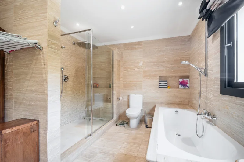 Salle de bains en travertin avec douche à l’italienne et baignoire