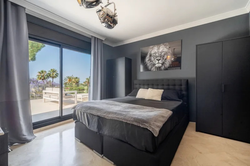 Chambre aux murs sombres avec une gravure de lion, ouvrant sur la terrasse