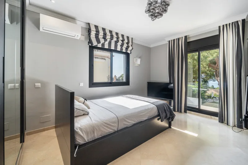 Chambre avec store bateau rayé, porte donnant sur la terrasse et un aperçu de la mer