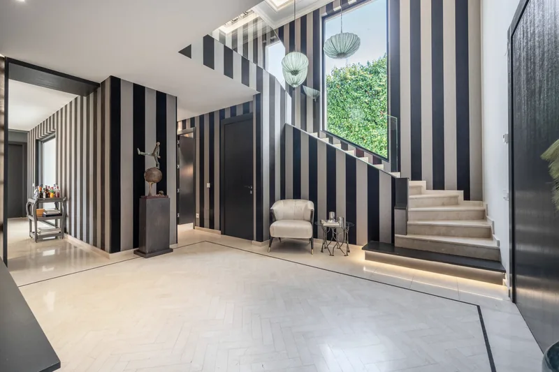 Hall d’entrée au papier peint rayé, avec l’escalier