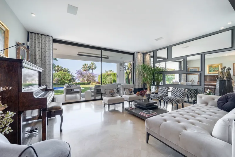 Salon avec piano et baie vitrée donnant sur la piscine