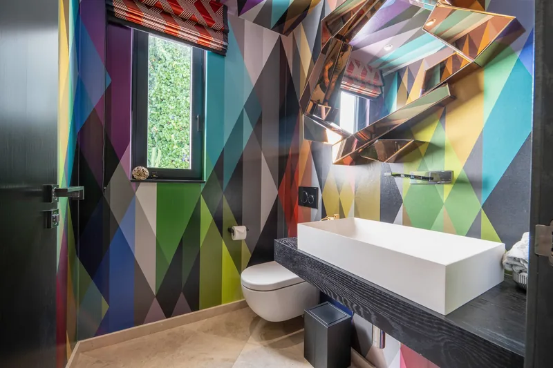 WC d’invités avec papier peint géométrique multicolore et applique à miroir