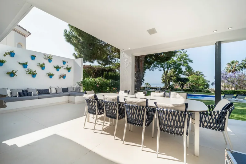 Terrasse couverte avec une table de repas pour dix, face à la mer