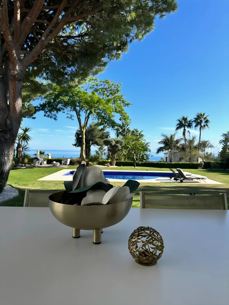 Une table avec une coupe en laiton, la piscine et la mer au-delà